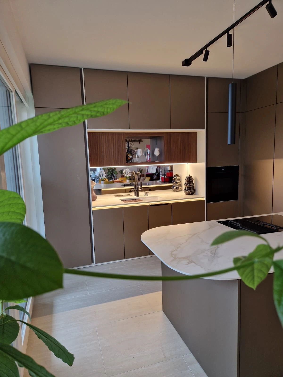 Moderne offene Küche mit Kochinsel, Marmorarbeitsplatte und großen Schränken.