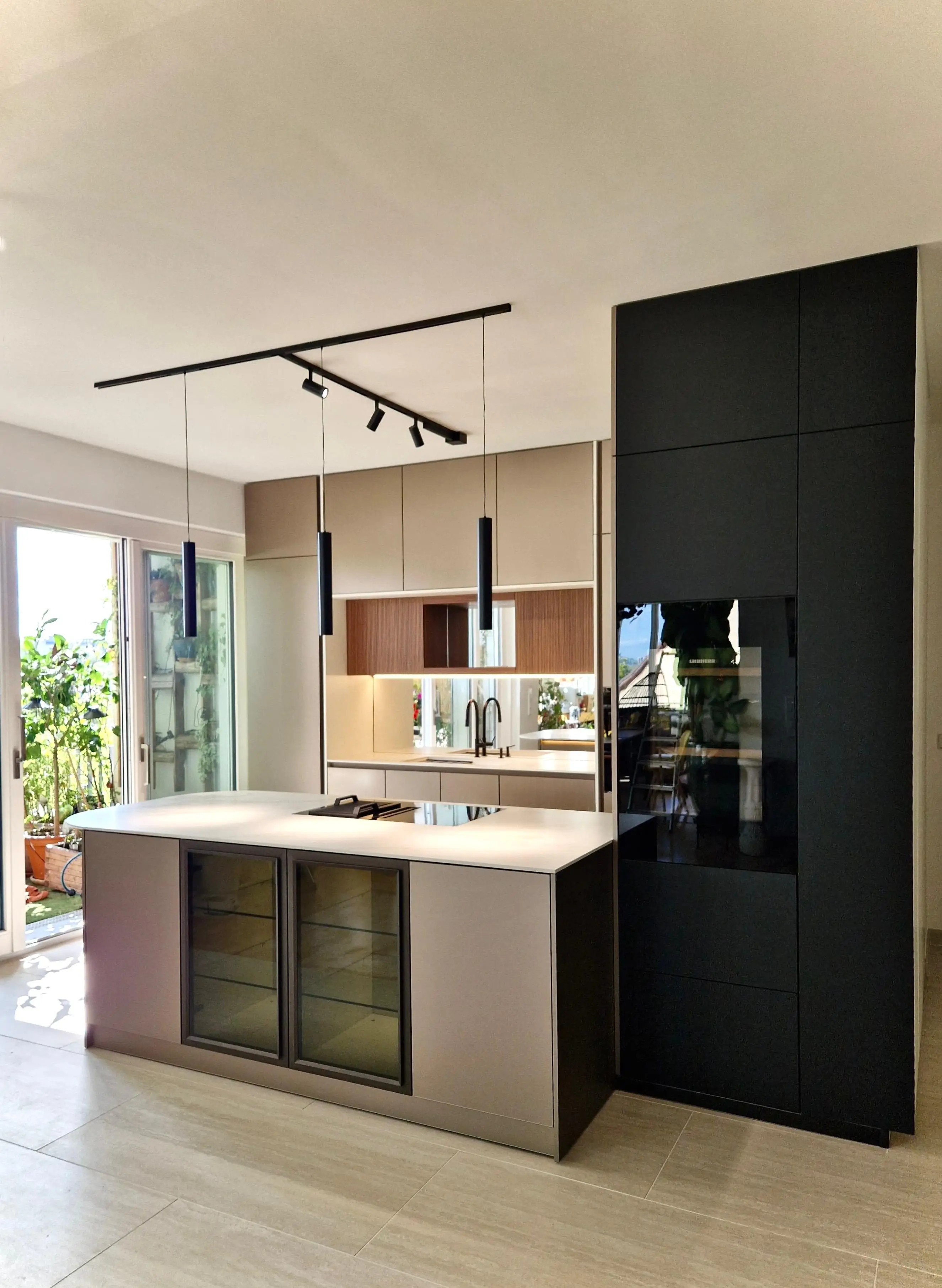 Moderne offene Küche mit Kücheninsel, Hängelampen und großen Fenstern für viel Licht.