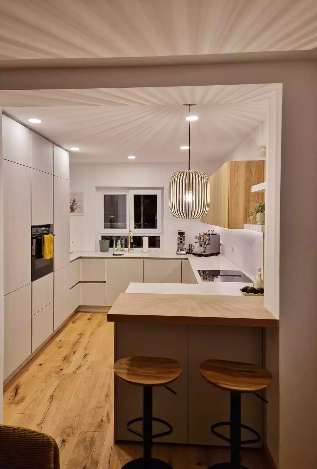 Moderne, helle Einbauküche mit Holztheke, Hängelampe und stilvollen Küchenmöbeln.