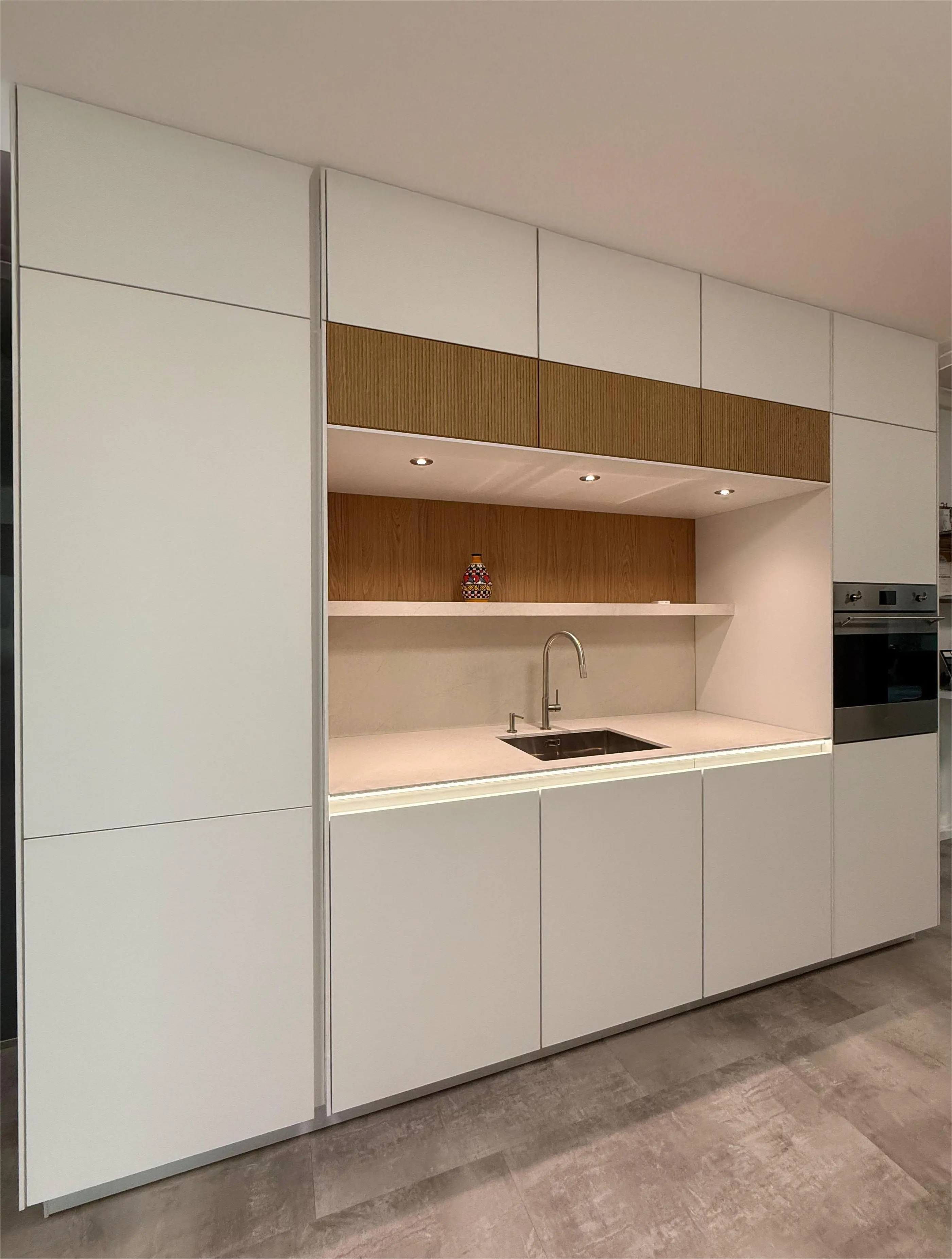 Moderne Einbauküche mit weißen Fronten, Holzdekor und integrierter Spüle.