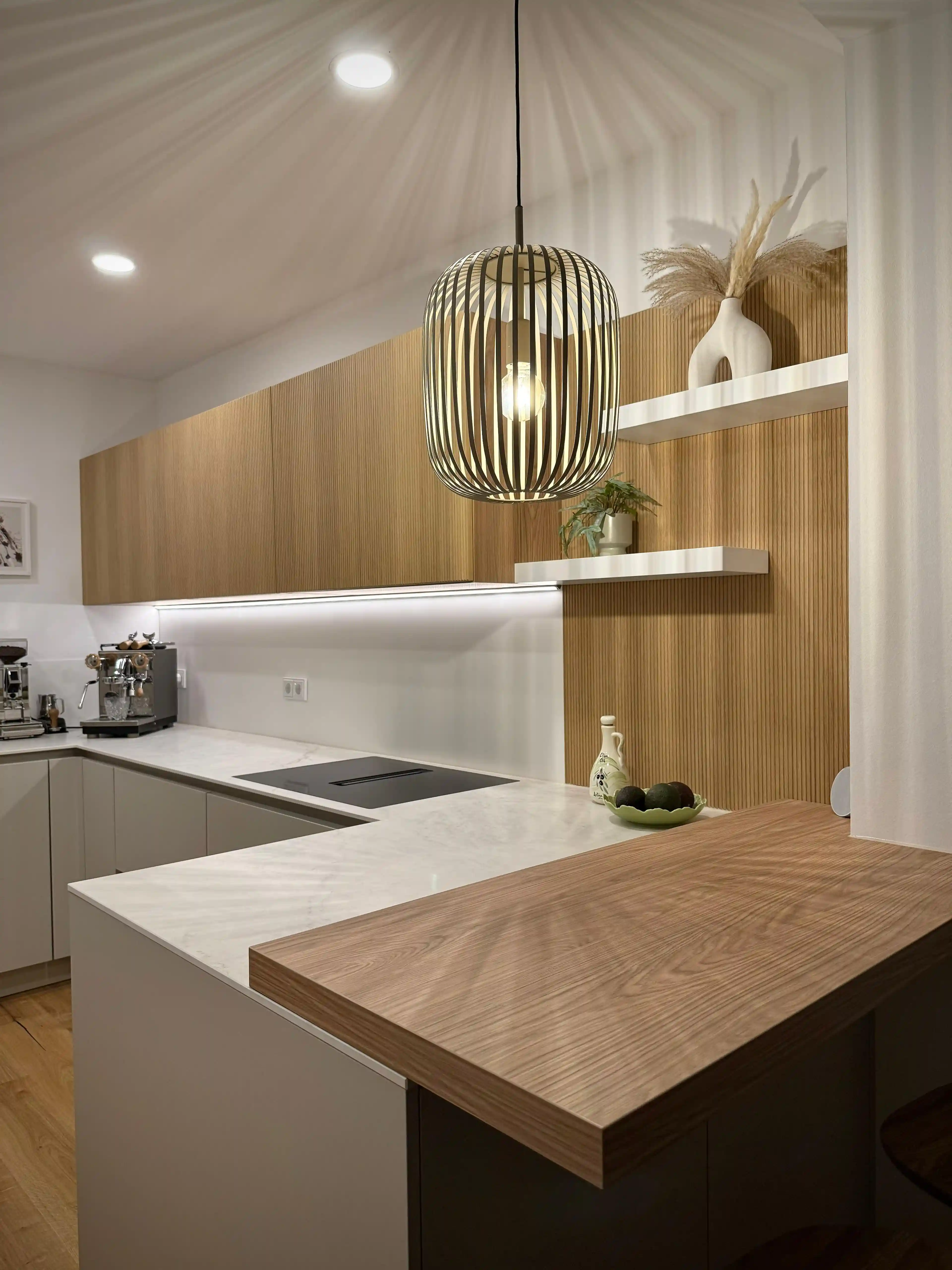 Moderne Küche mit Holzfronten, Marmorarbeitsplatte und stilvoller Hängelampe.